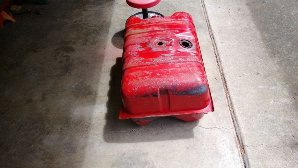 Red fuel tank resting on a red stool on a concrete floor