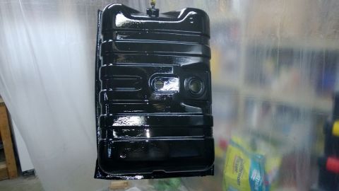 1983 Ford Bronco - A freshly painted black fuel tank hangs, ready for installation on a vehicle.