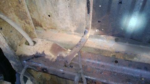 1983 Ford Bronco - Heavily rusted vehicle frame shows significant corrosion and a wire conduit.