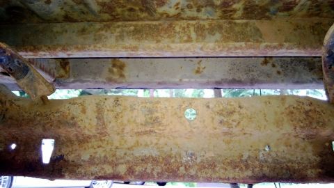 1983 Ford Bronco - The heavily rusted frame of a vehicle is shown from underneath.