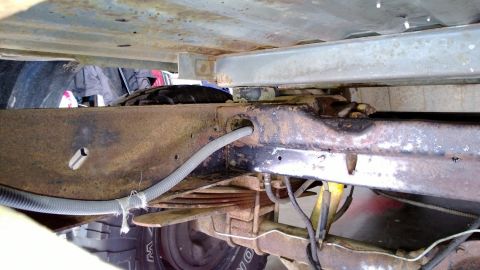 1983 Ford Bronco - The undercarriage of a 1983 Ford Bronco reveals its frame, leaf springs, and a portion of the tire.