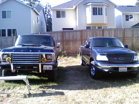 1979 Ford Bronco - Two Ford trucks parked in a yard, one is a 1979 F-Series and the other is a newer F-150.