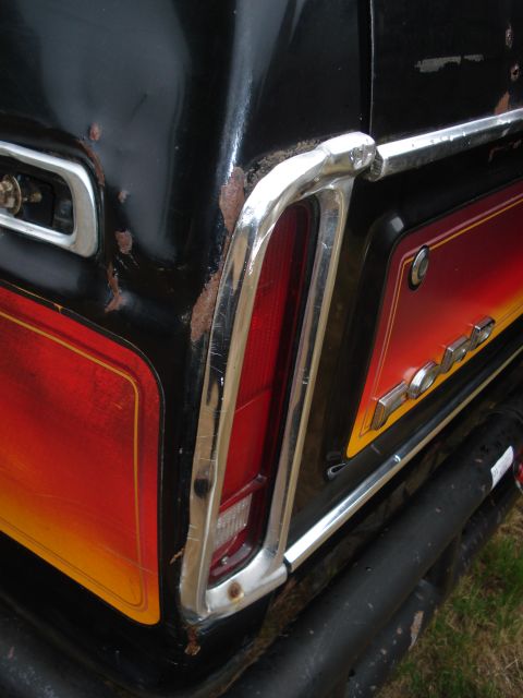 1979 Ford Bronco - Close-up of the rear quarter panel of a black 1979 Ford Bronco, showing its distinctive stripe and chrome accents.