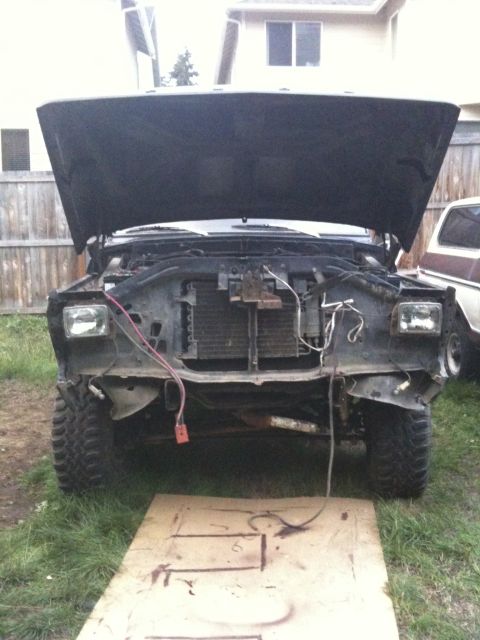 1979 Ford Bronco - The front of a truck is disassembled with the hood open, revealing the engine bay and radiator.