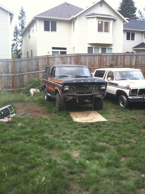 1979 Ford Bronco - A 1979 Ford Bronco sits in a yard with its front end disassembled, next to another vehicle.