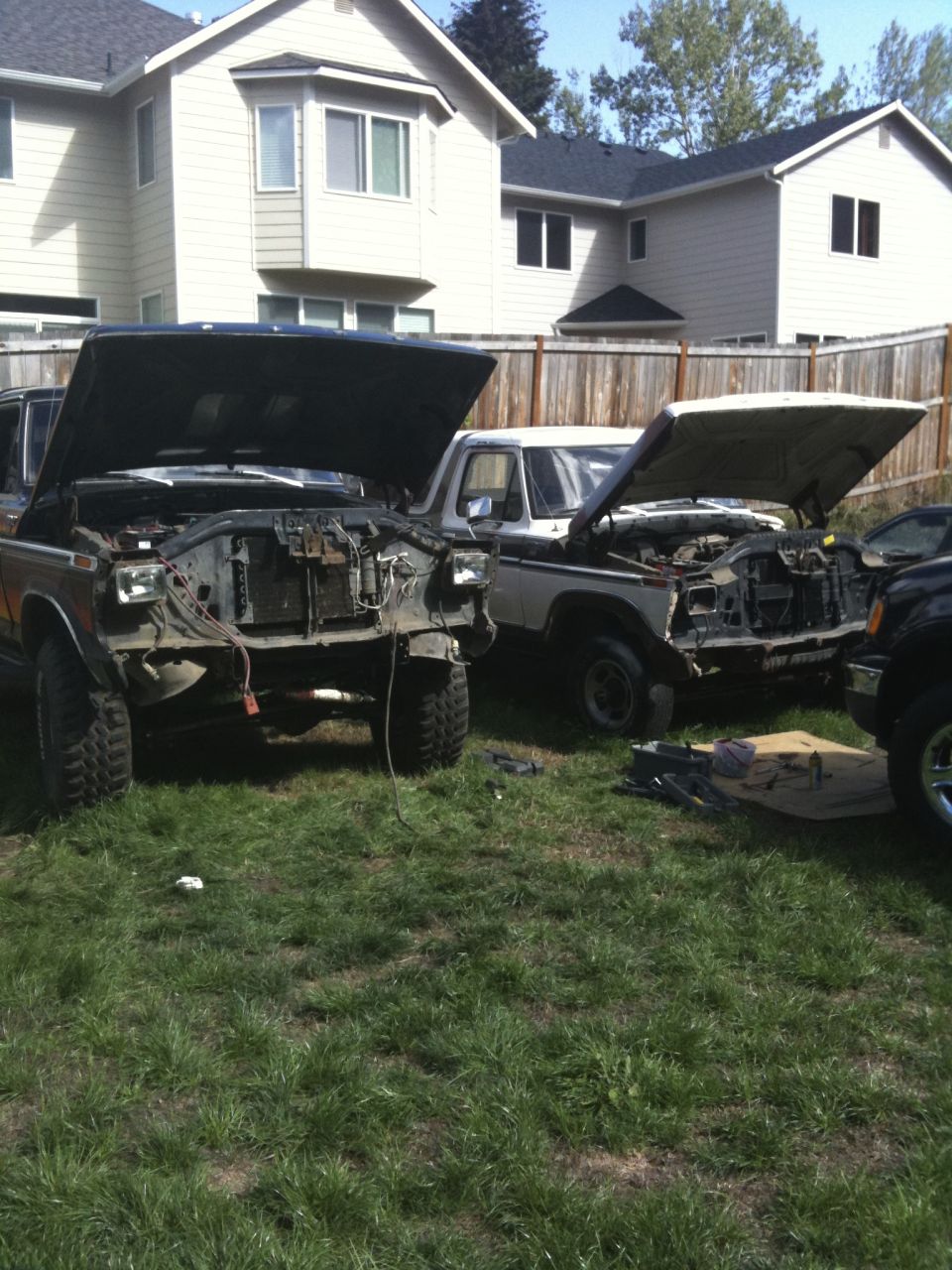 Brown and white SUVs with hoods open in a yard