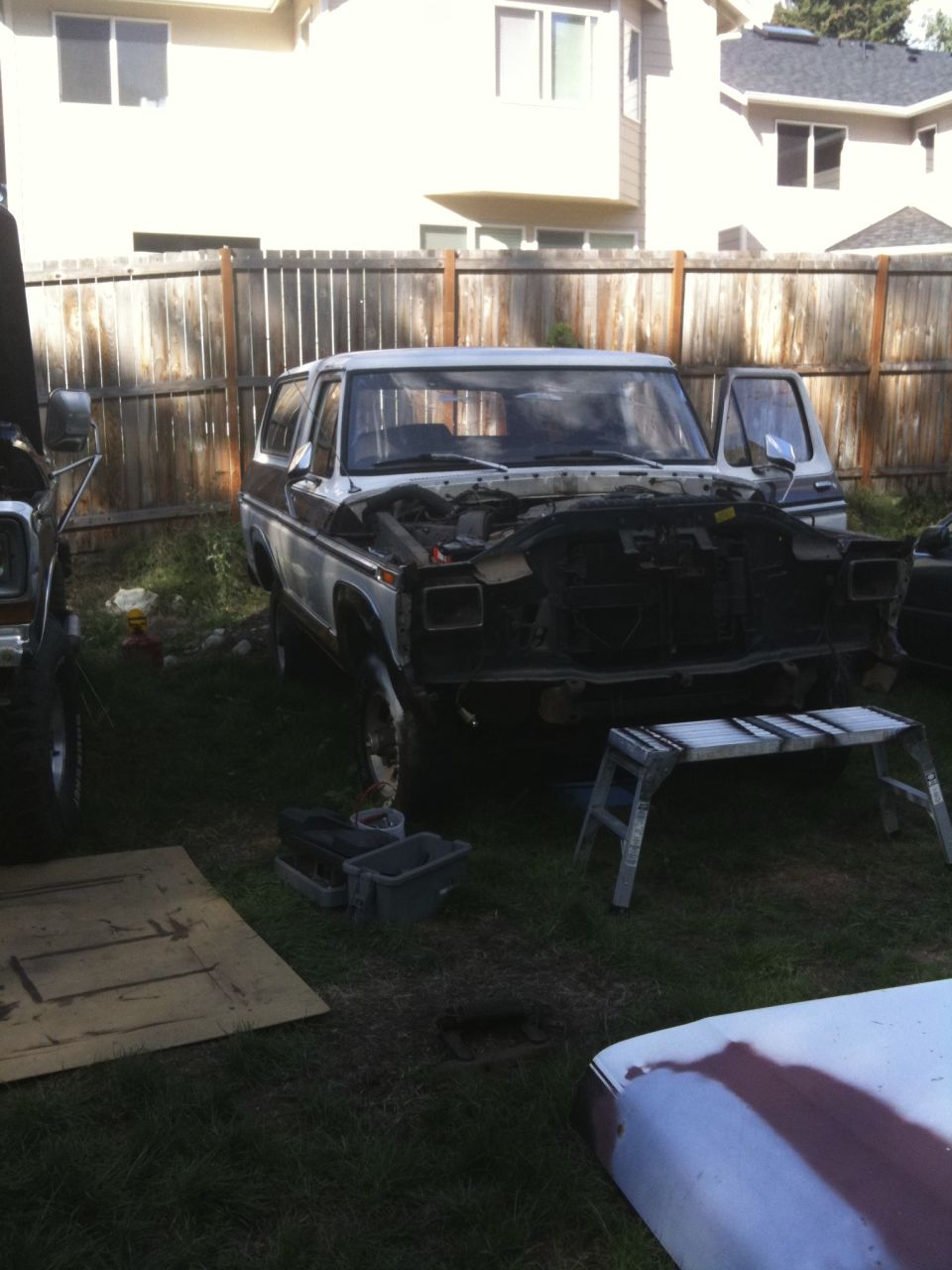 Ford Bronco with hood open, parked in a yard with another vehicle partially visible