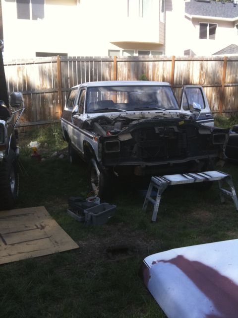 1979 Ford Bronco - A two-tone brown and white Ford Bronco sits in a yard with its hood open, showing signs of repair or modification.