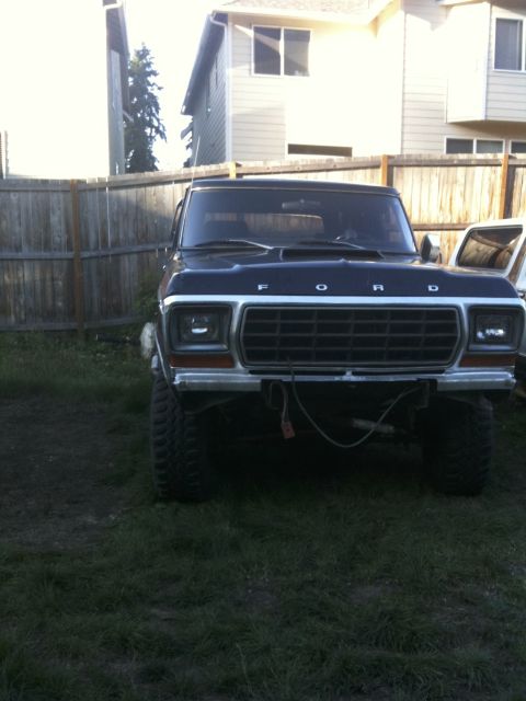 1979 Ford Bronco - This black Ford Bronco is parked in a grassy yard with a wooden fence behind it.
