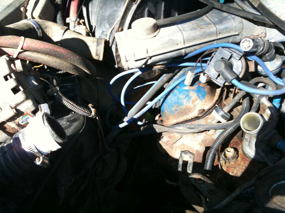Engine bay with hoses, wires, and engine components visible