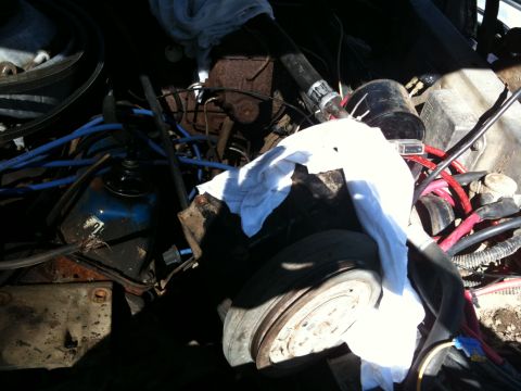 1979 Ford Bronco - A cluttered engine bay with various components and wiring, partially obscured by a white cloth.