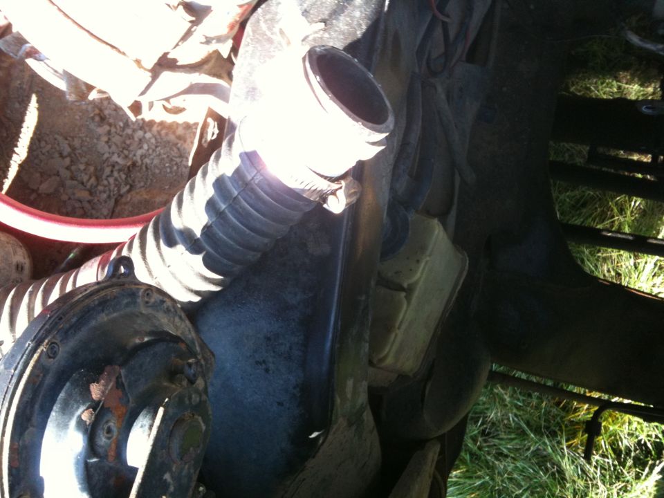 Close-up of ribbed hose and black circular component in engine bay