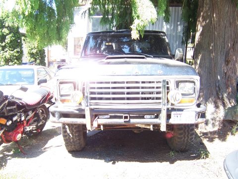1979 Ford Bronco - Front view of a 1979 Ford Bronco, equipped with a bull bar and auxiliary lights. A motorcycle is visible to the left.