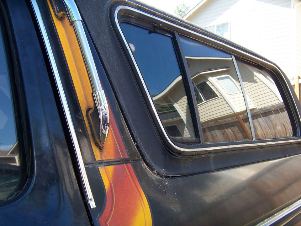 Black 1979 Ford Bronco side window with chrome trim and flame decal detail