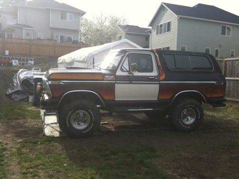 1979 Ford Bronco - A lifted 1978 Ford Bronco with a two-tone paint scheme sits parked on a grassy area.