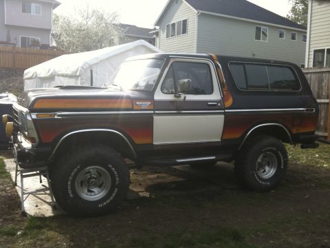 1979 Ford Bronco - This 1979 Ford Bronco features a distinctive two-tone paint scheme with wood paneling and racing stripes.