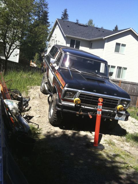 1979 Ford Bronco - 1979 Ford Bronco parked on an uneven dirt surface, with a residential building behind it.