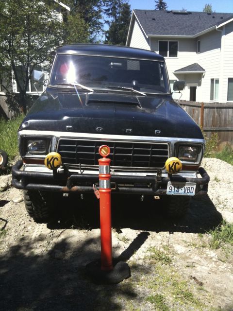 1979 Ford Bronco - A black 1978 Ford Bronco is parked outdoors, facing the camera, with aftermarket lights and a license plate visible.