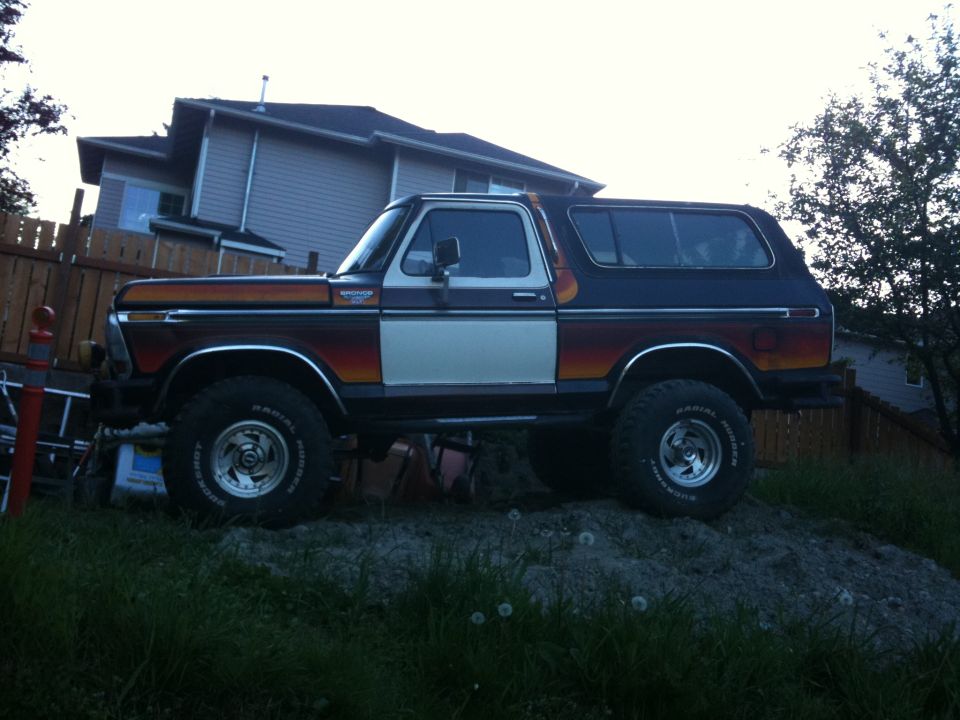 1979 Ford Bronco parked on a dirt mound, side view. Two-tone paint with orange and white