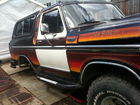 1979 Ford Bronco - This Ford Bronco features a distinctive two-tone paint scheme with orange and red gradient stripes along the body.