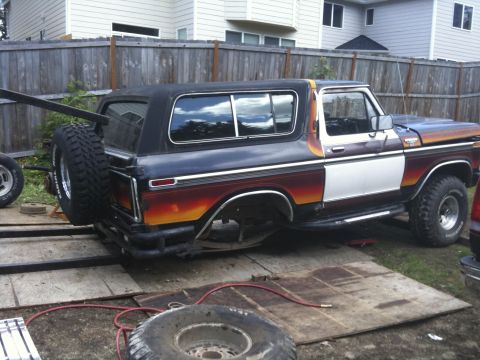 1979 Ford Bronco - Ford Bronco with custom paint job and external spare tire is parked on a trailer outdoors.