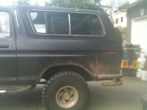 1979 Ford Bronco - This black 1979 Ford Bronco is shown from the side, a camper shell and off-road tires.