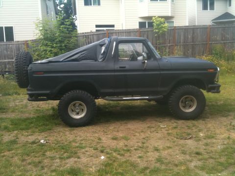 1979 Ford Bronco - This 1979 Ford Bronco is seen from the side, a spare tire on the back and a tarp covering the rear section.