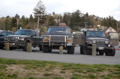 1979 Ford Bronco - Three trucks and SUVs are parked in a row on a street.