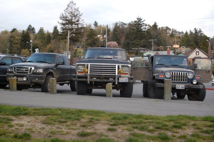 Black Ford Ranger, dark pickup truck, and blue Jeep Wrangler parked side-by-side