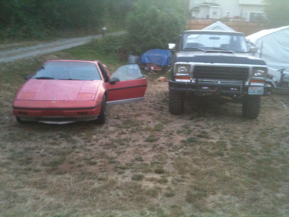 Red sports car with door open next to a black pickup truck. The truck has a license plate that reads C14-300