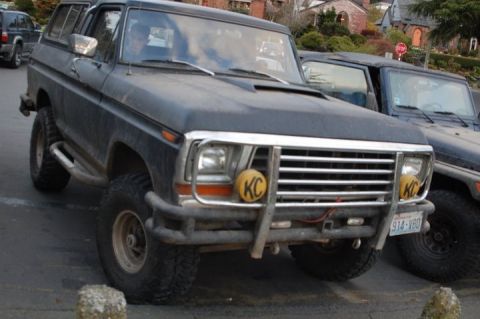 1979 Ford Bronco - This lifted 1978 Ford Bronco features KC lights and off-road tires, parked on a street.