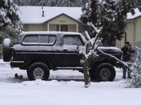 1979 Ford Bronco - A black 1979 Ford Bronco sits covered in snow, parked in front of a house.