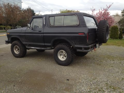 1979 Ford Bronco - This black Ford Bronco is seen from the rear three-quarter view, parked outdoors on a cloudy day.