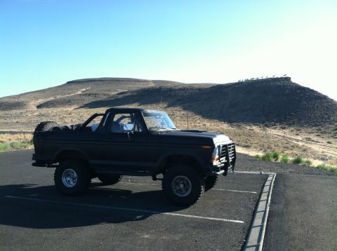 1979 Ford Bronco - A black Ford Bronco is parked in a lot with a desert landscape in the background.