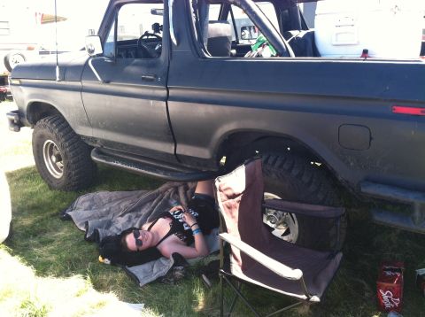 1979 Ford Bronco - A person lies on the ground beneath a black 1979 Ford Bronco, possibly for repairs or shade.