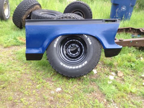 1979 Ford Bronco - A blue truck bed section sits on the grass with spare tires nearby.