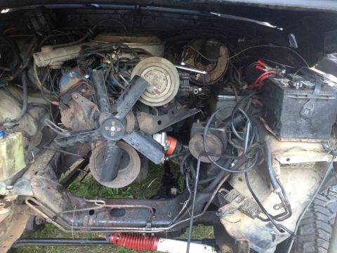 1979 Ford Bronco - The engine bay of a 1979 Ford Bronco, showing the fan, battery, and various engine components.