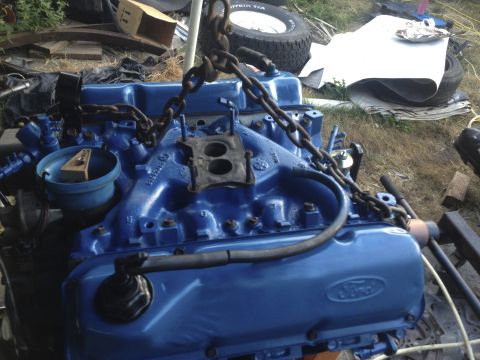 1979 Ford Bronco - Engine block painted bright blue, suspended by chains, with a Ford logo visible on the side.