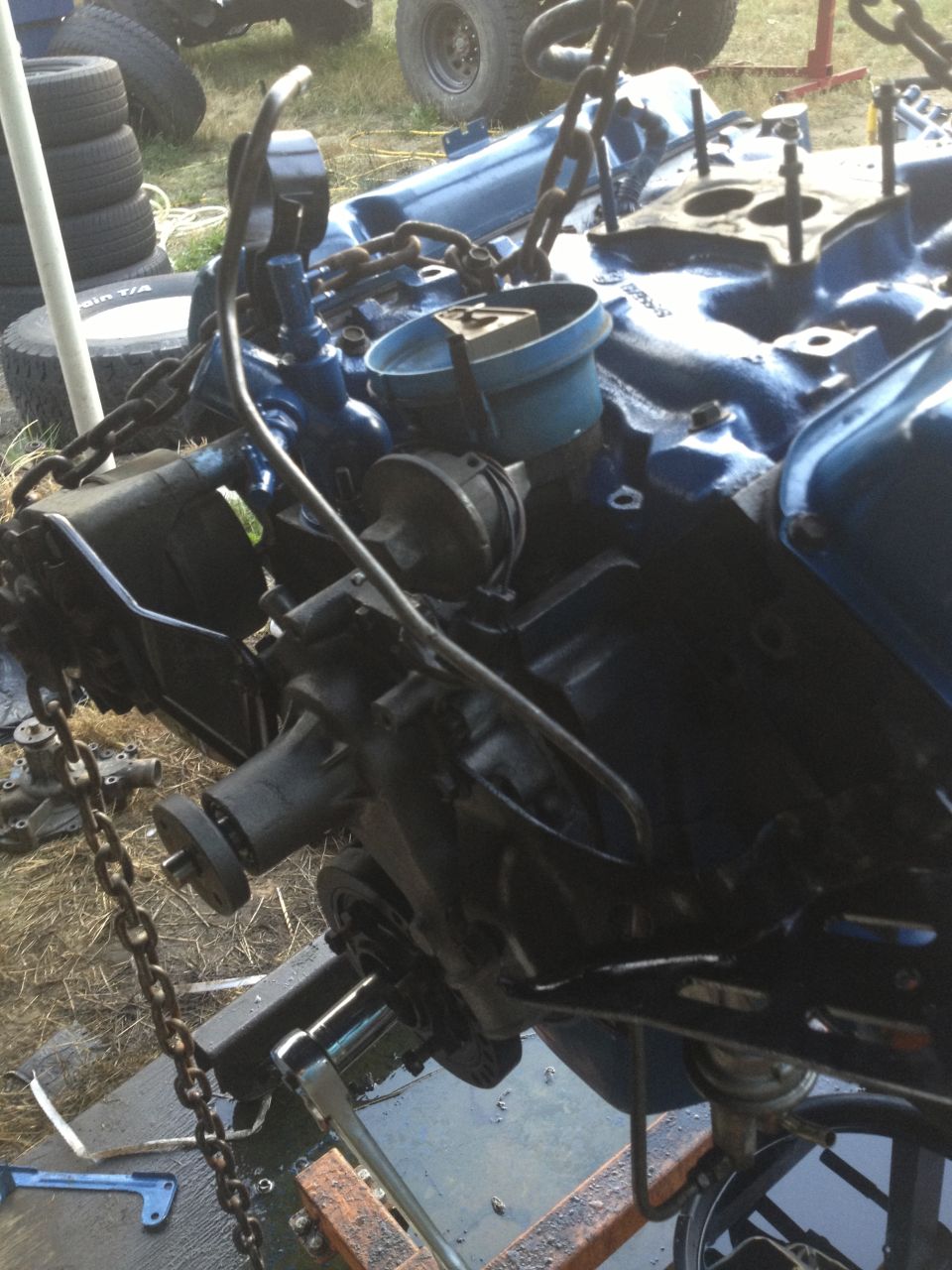 Engine block assembly suspended by chains, with various components attached