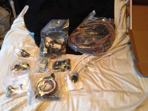 1979 Ford Bronco - Various electrical parts and wiring harnesses are organized in plastic bags on a white blanket.