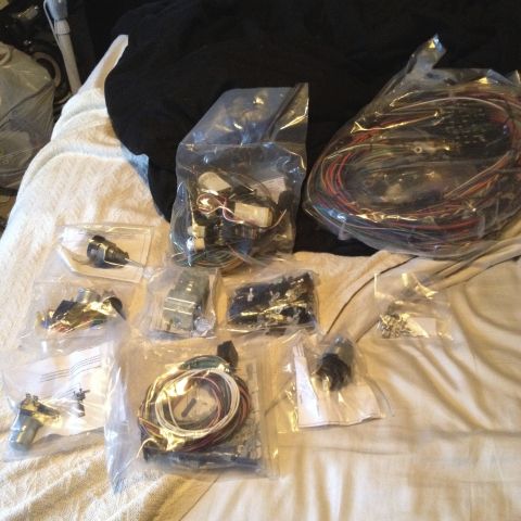 1979 Ford Bronco - Various electrical parts and wiring harnesses are organized in plastic bags on a blanket.