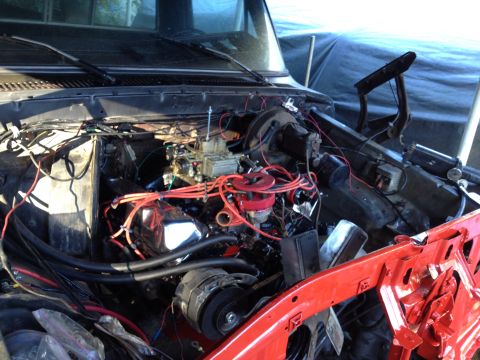 1979 Ford Bronco - The engine bay of a vehicle is shown with prominent red spark plug wires and a carburetor, suggesting a build or repair process.