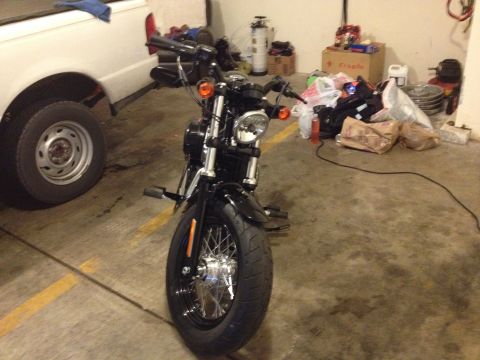 1979 Ford Bronco - A black motorcycle is parked in a garage next to a white pickup truck, with various items stored in the background.