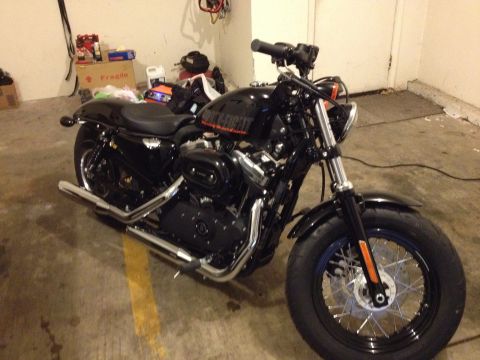 1979 Ford Bronco - Black Harley-Davidson motorcycle with chrome exhaust pipes and orange reflectors on the front forks.