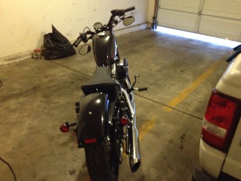 1979 Ford Bronco - A black motorcycle is parked in a garage next to a white vehicle.