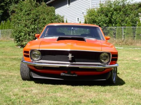 1979 Ford Bronco - Front view of an orange classic Ford Mustang with a prominent hood scoop and chrome bumper.