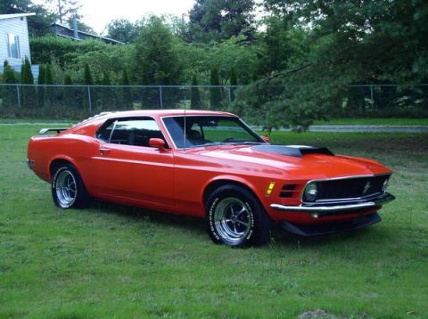 1979 Ford Bronco - A classic red Ford Mustang is shown from a three-quarter front view, parked on a grassy lawn.