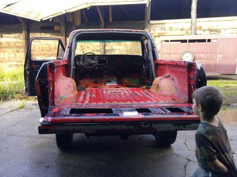 Red pickup truck interior and bed, doors open, showing rust and wear