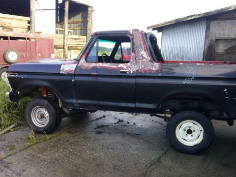 1978 Ford Bronco - Side view of a 1978 Ford Bronco with visible rust and primer on the body panels.