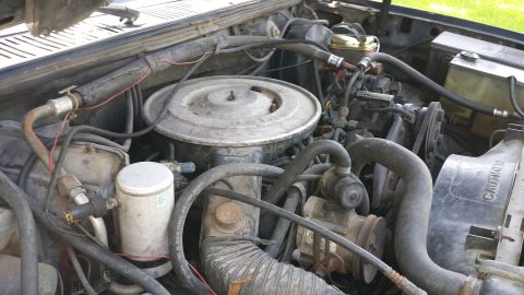 1984 Ford Bronco - Close-up view of an engine bay, showing various components and hoses. The fan shroud has 'CAUTION' text.